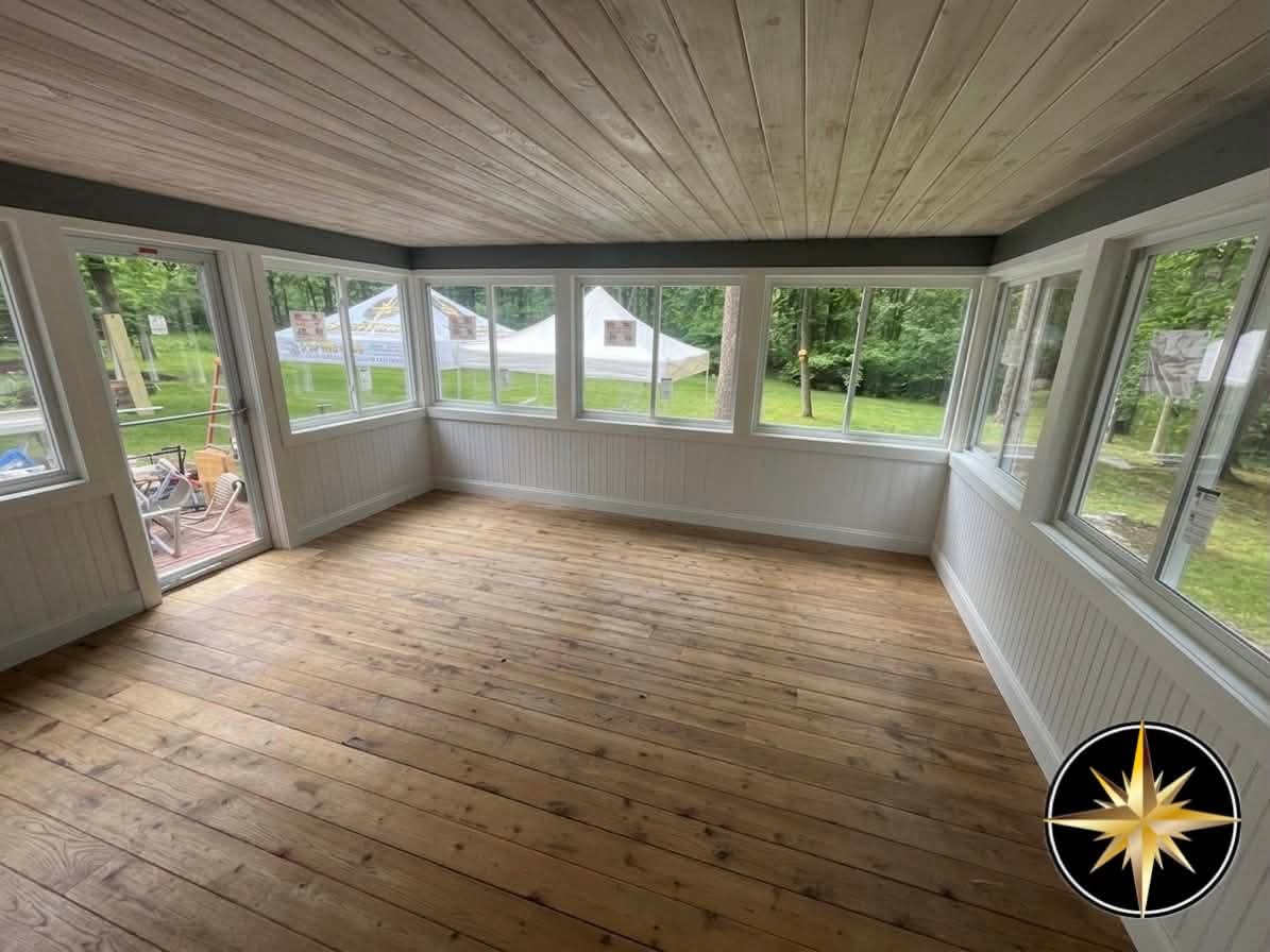 Interior of the finished Atkinson, NH sunroom with natural pine plank ceiling, beadboard wainscot, and a wall of windows