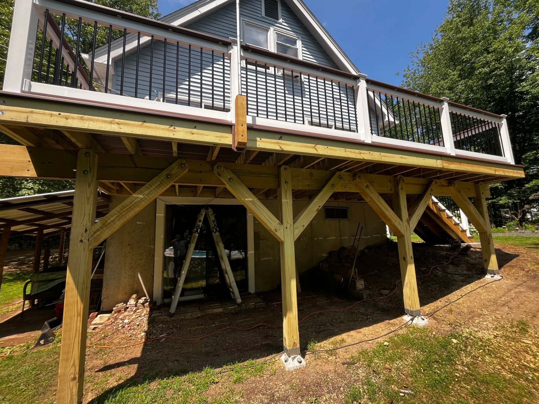 Wide elevation view of the finished elevated Wolf composite deck in Nottingham, NH with white posts and black aluminum balusters